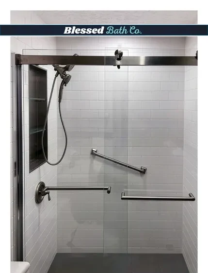 Walk-in shower with a matte black door, handheld showerhead on a slide bar and black grab bars