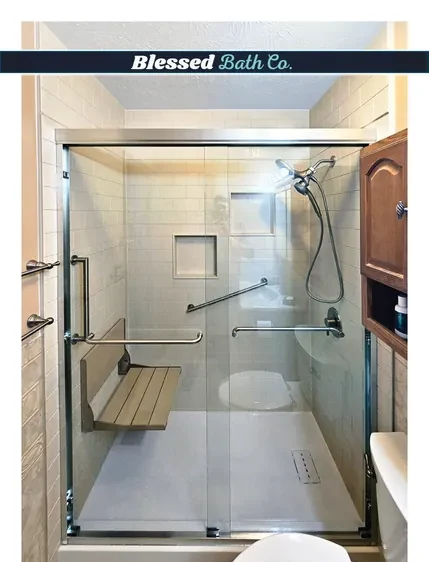 Walk-in shower with a chrome-framed sliding glass door, fold-down seat and grab bars