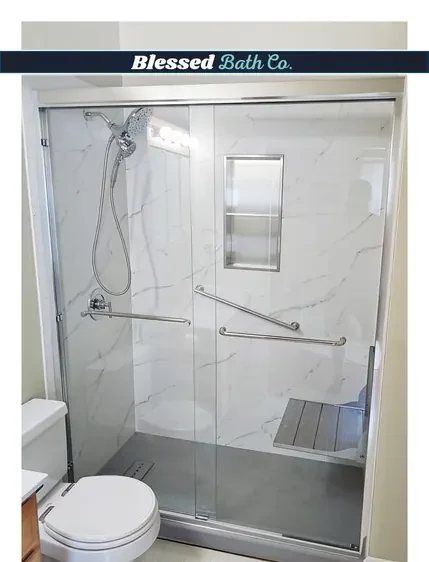 Walk-in shower with a chrome sliding glass door, tall niche and handheld showerhead