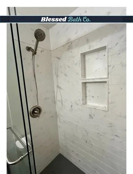 Marble-look shower walls with a recessed niche, grab bar and handheld showerhead
