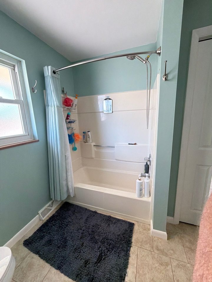 Before: an old white fiberglass tub with a shower curtain