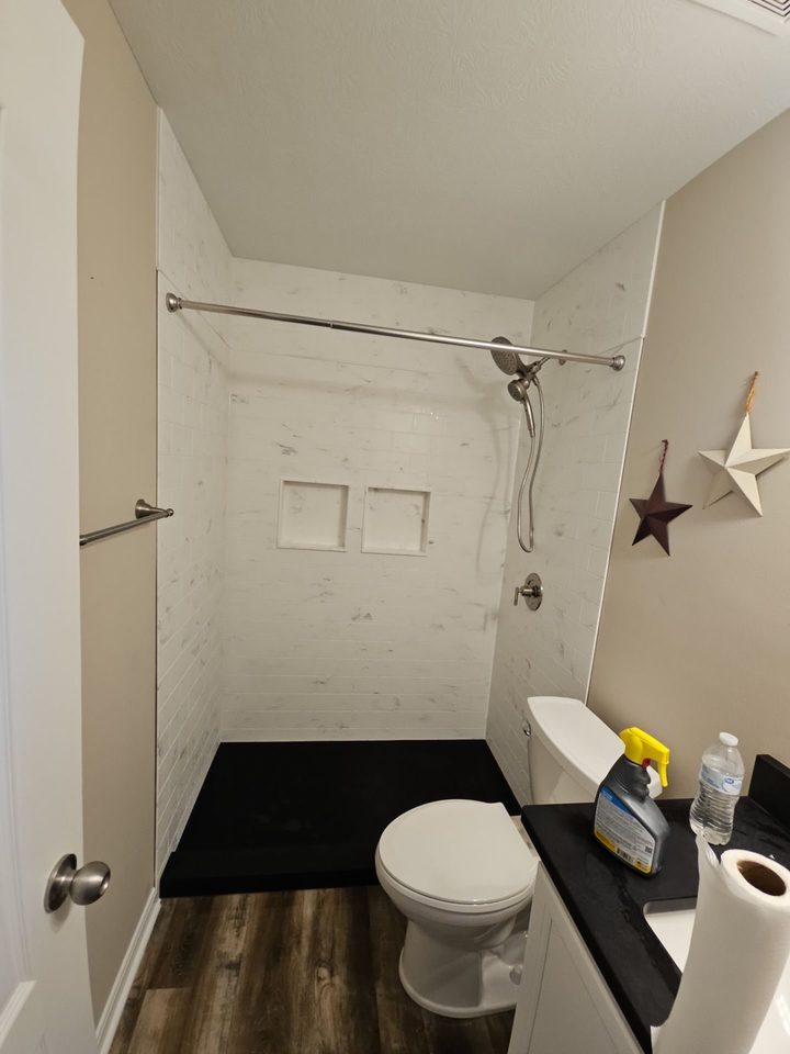 After: a walk-in shower with white subway-look walls and a matte black shower pan