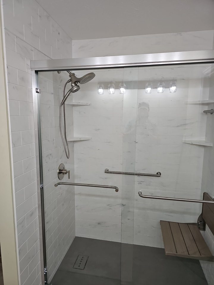 After: a walk-in shower with a fold-down teak seat, a sliding glass door and grab bars