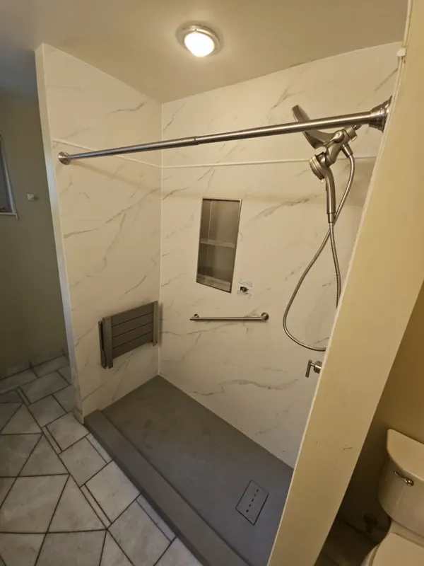 Walk-in shower with a fold-down seat, handheld shower and recessed niche