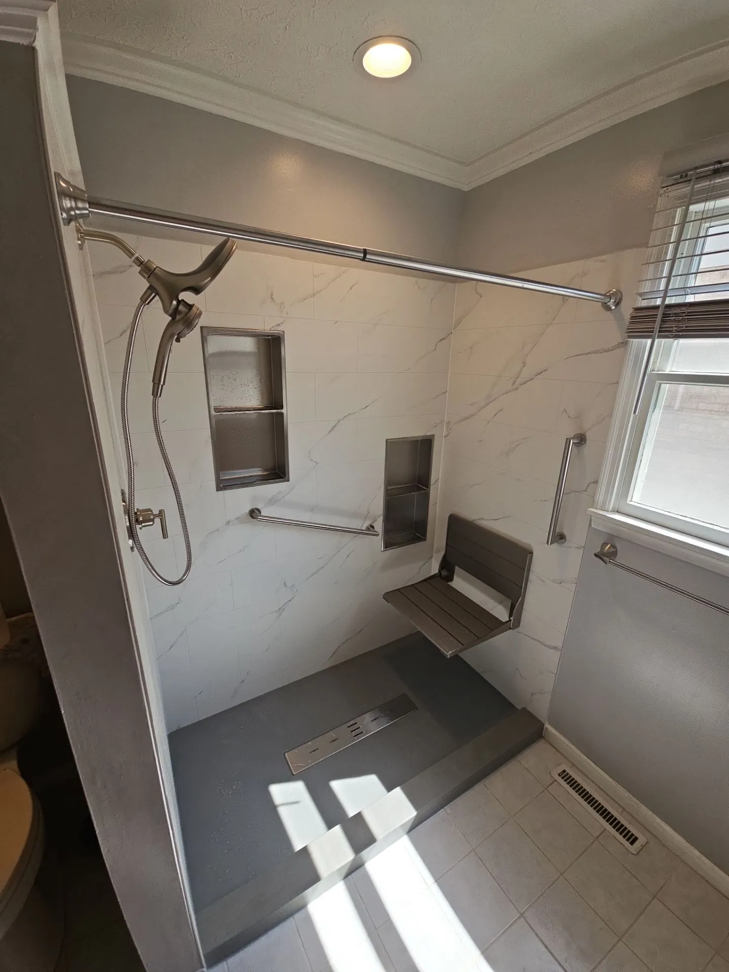 A tub replaced with a walk-in shower, fold-down seat and grab bars